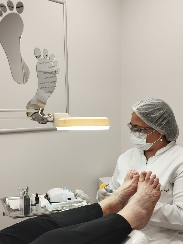 Dra. Ariane Baiak realizando tratamento de unha encravada em paciente, com biossegurança completa, em Santa Felicidade, Curitiba